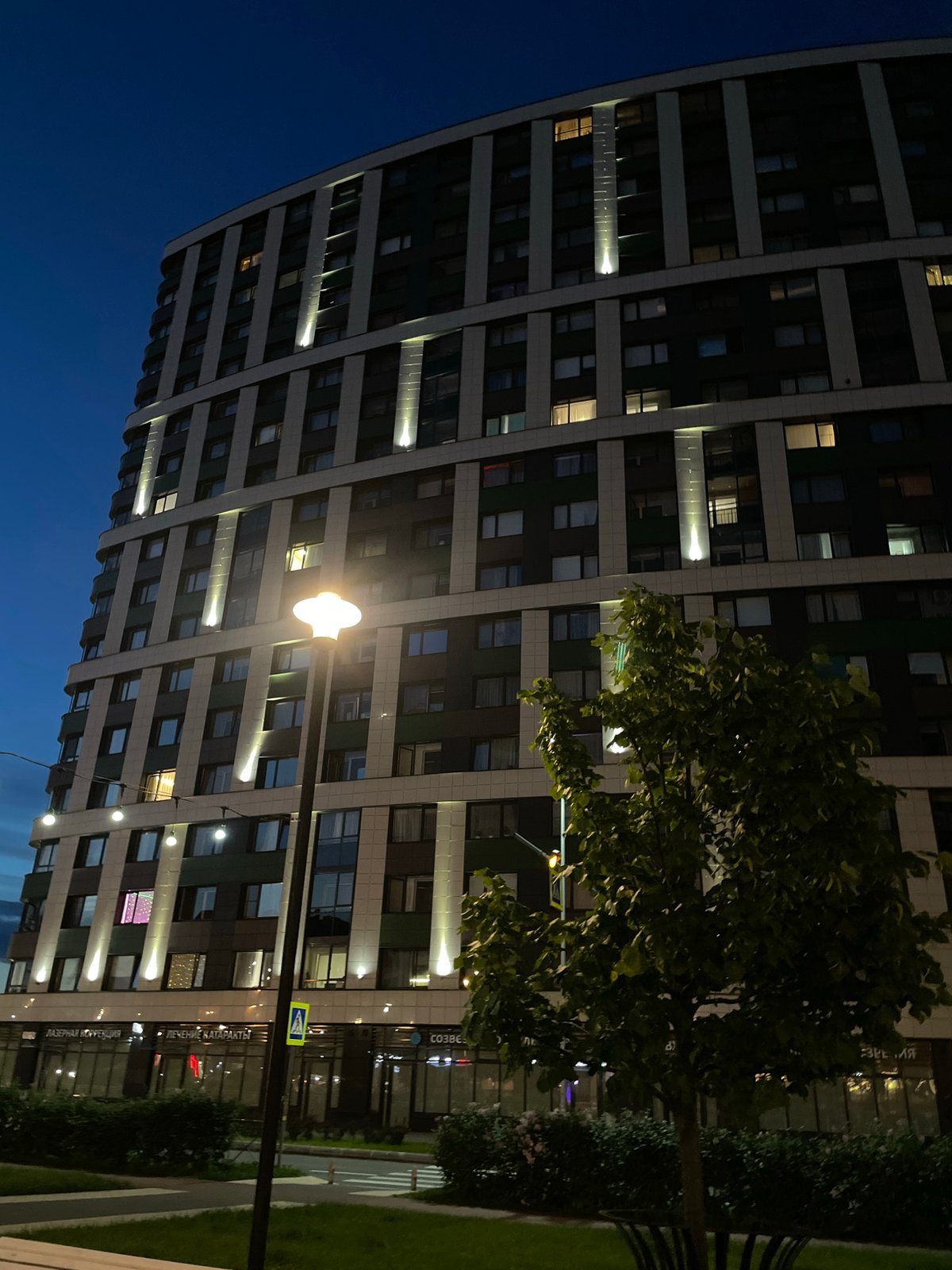 Modern high-rise building illuminated at dusk with glowing windows
