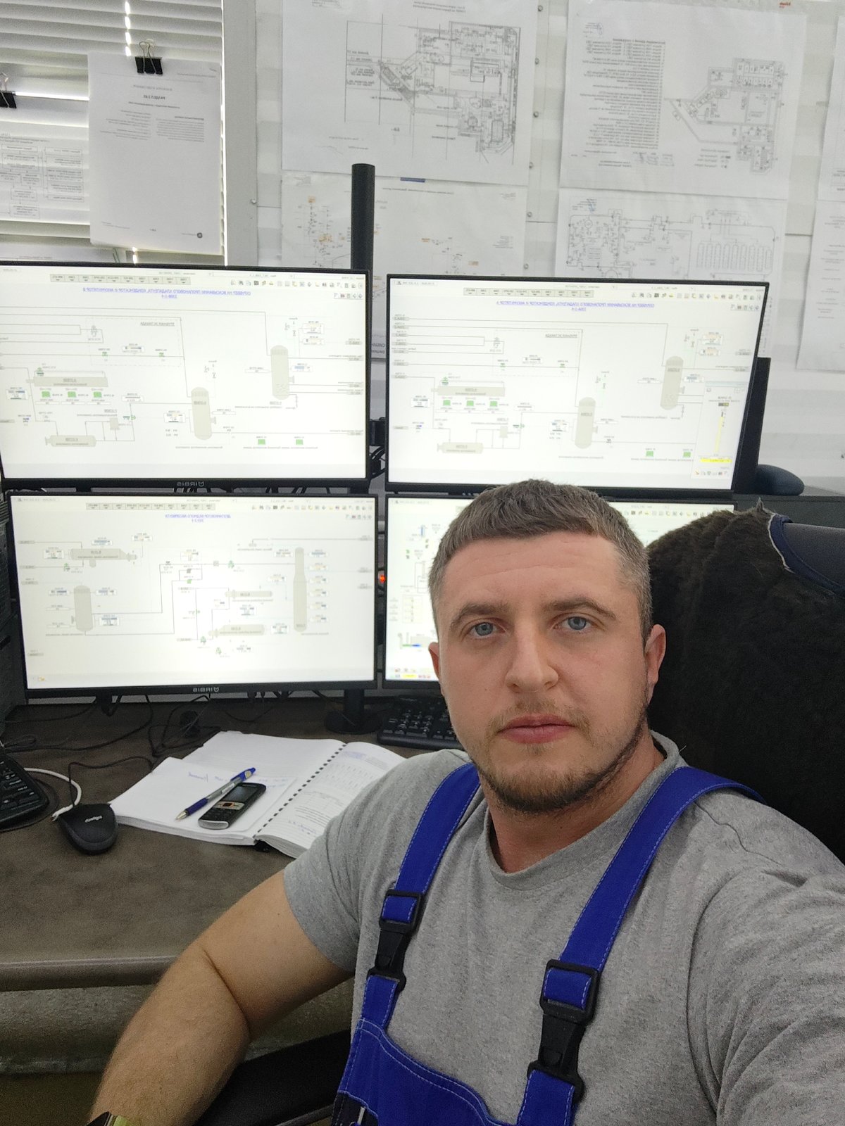 Worker monitors industrial processes from multi-screen control station