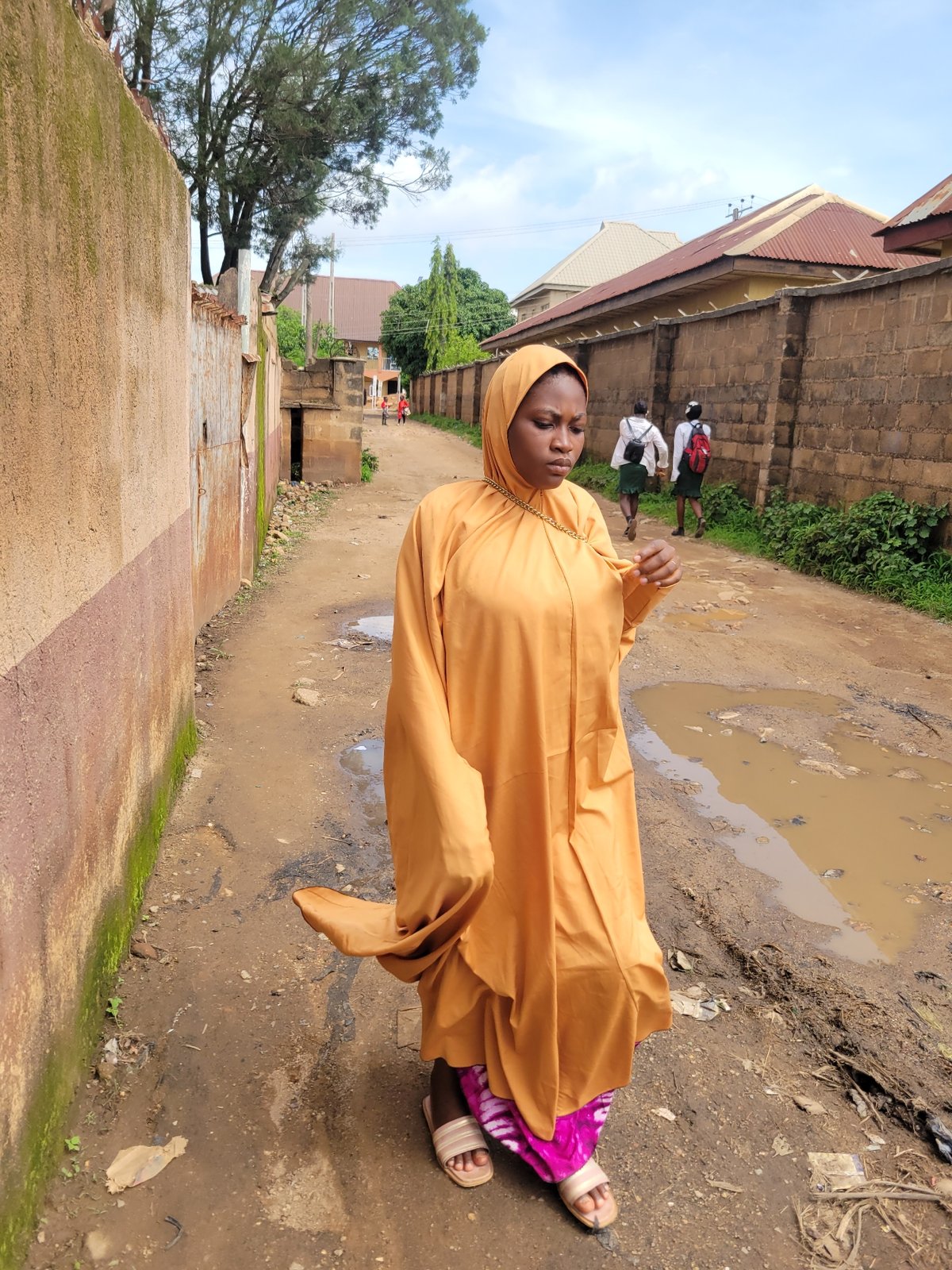 Everyday street life on a muddy Jos neighborhood road
