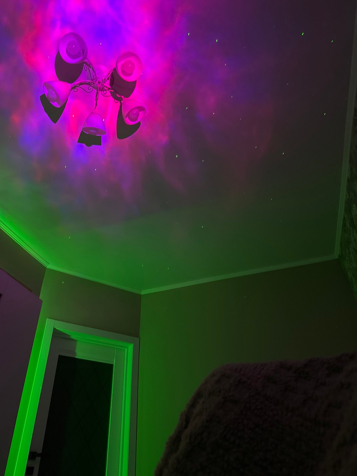 Room ceiling features cosmic nebula projection with chandelier centerpiece