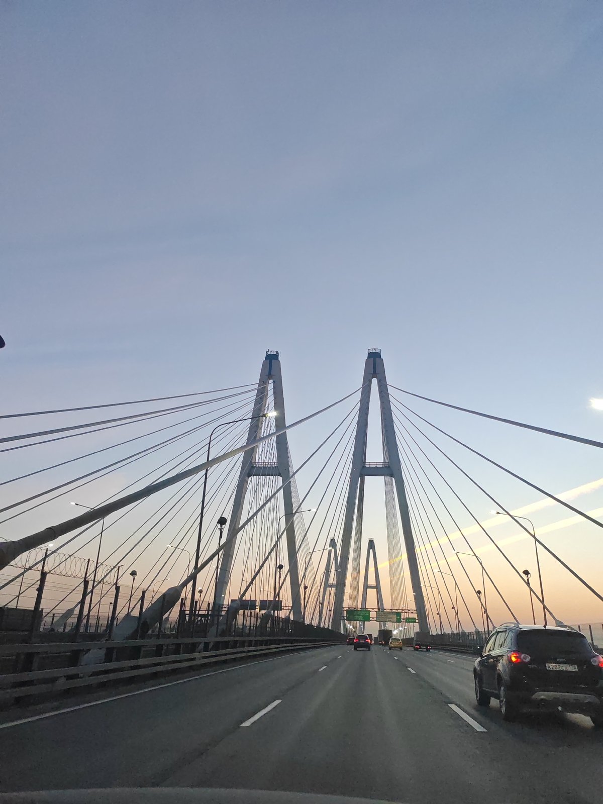 Traffic flows on highway approaching cable-stayed bridge in Novosaratovka