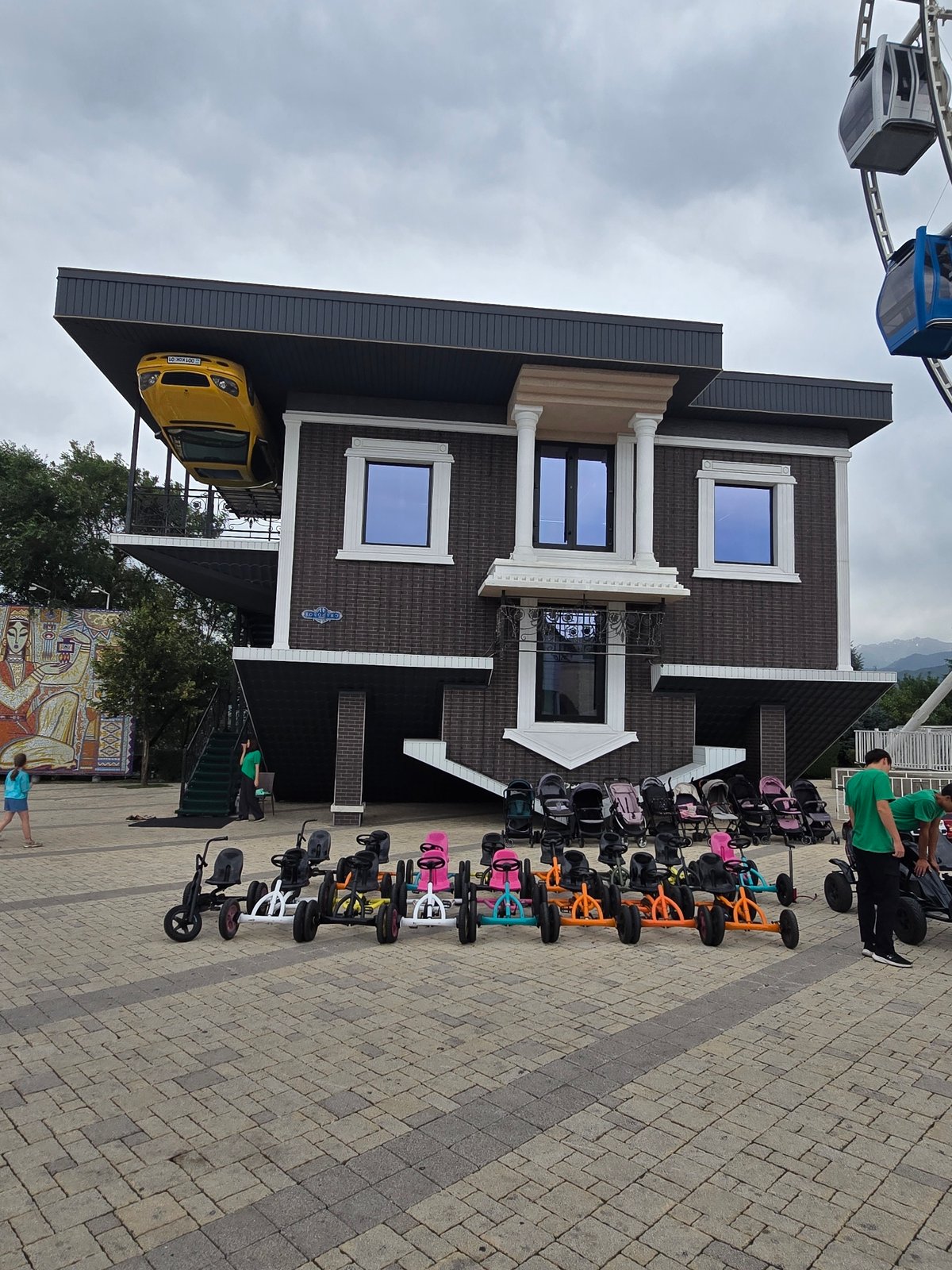 Ferris wheel and upside-down house at Almaty amusement park