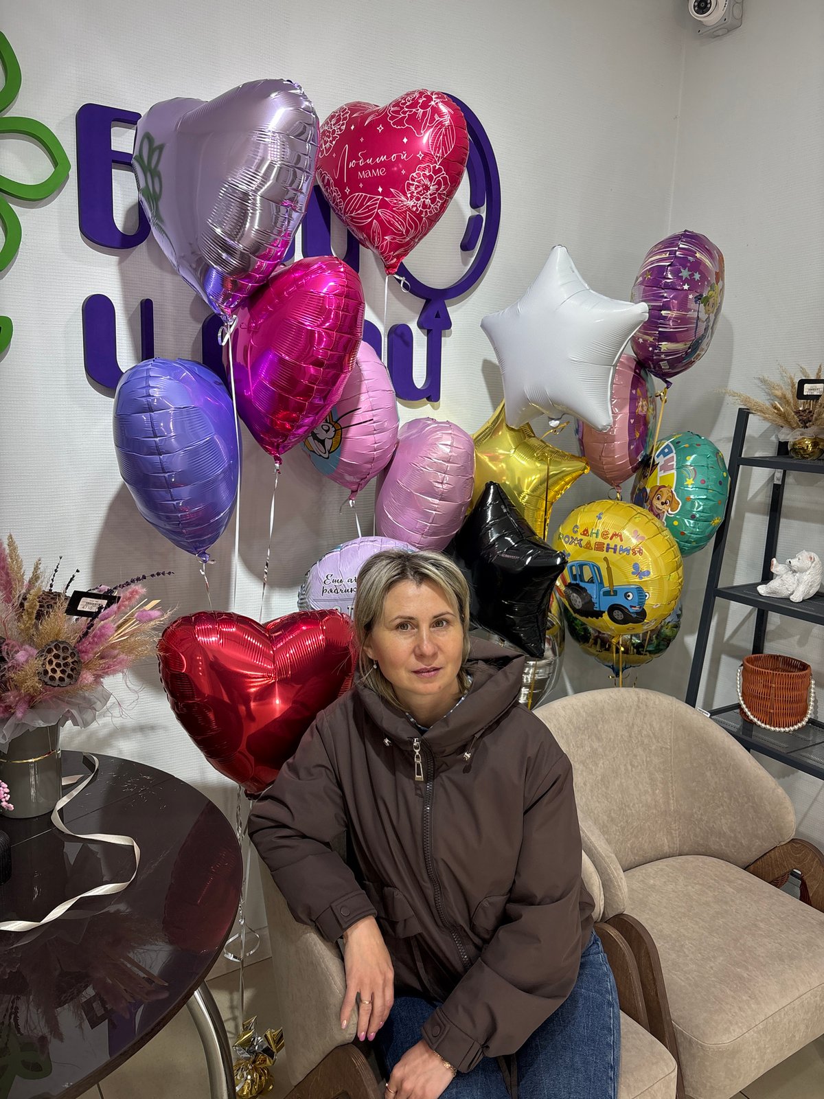Celebration gathering captured at Nizhnevartovsk shop with balloons, flowers