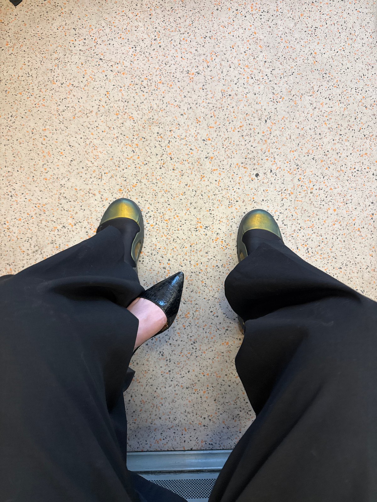 Person in black trousers seated in London public space
