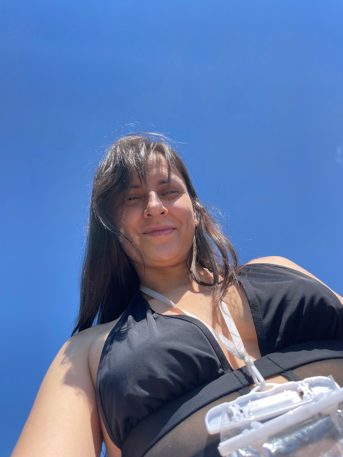 Low-angle poolside portrait against open blue sky