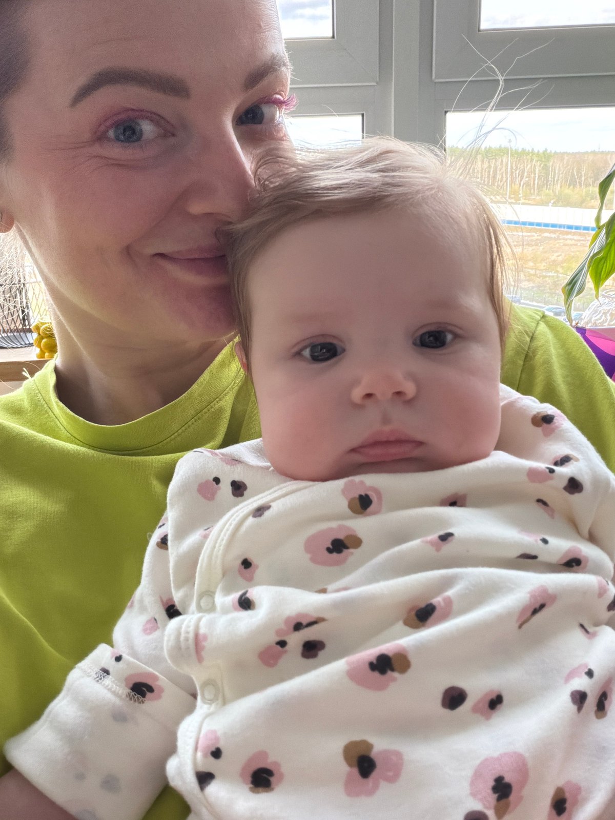 Adult holds infant in white floral onesie in Podolsk