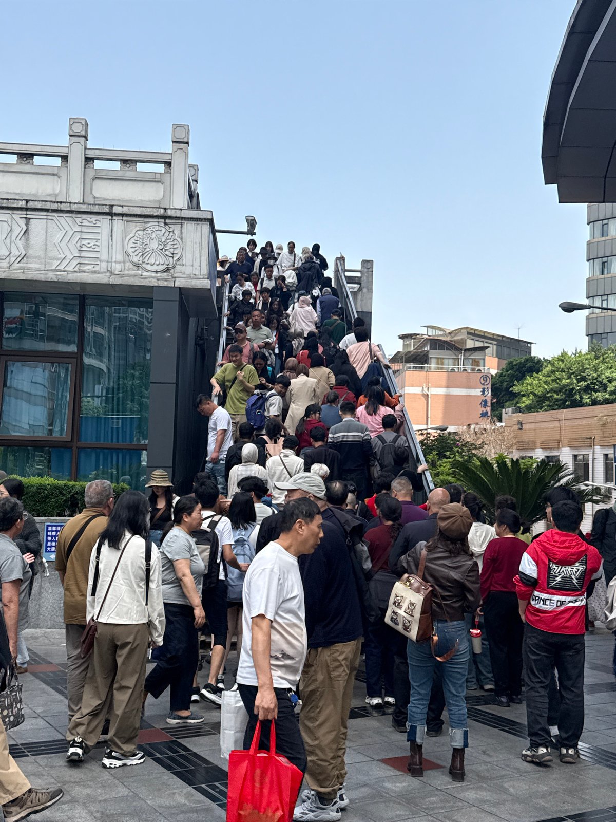 Dense crowd queues in Yuzhong District, wheelchair user assisted