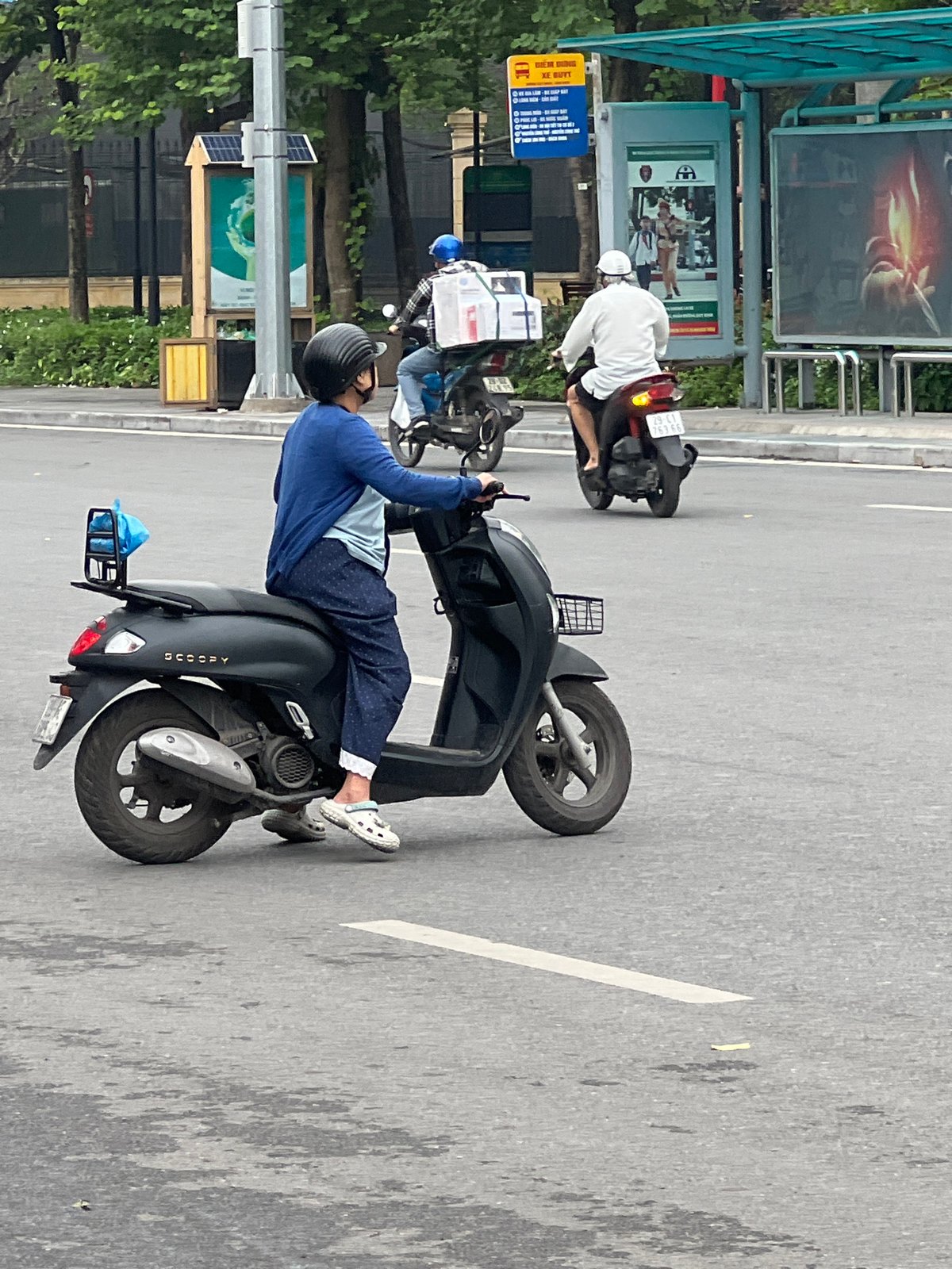 Wet morning scooter traffic on a Hanoi city street
