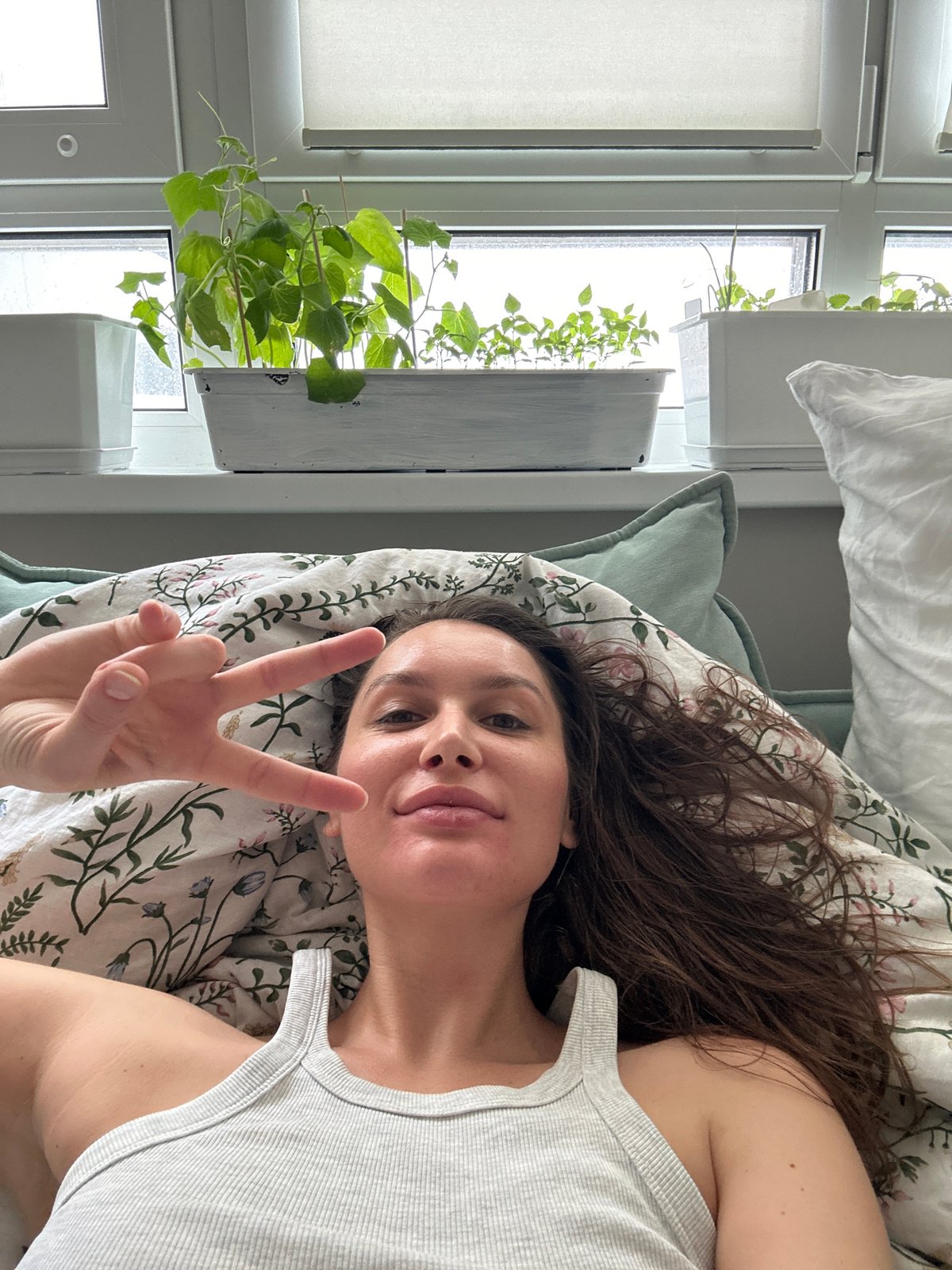 Woman makes peace sign gesture on bed in Khimki