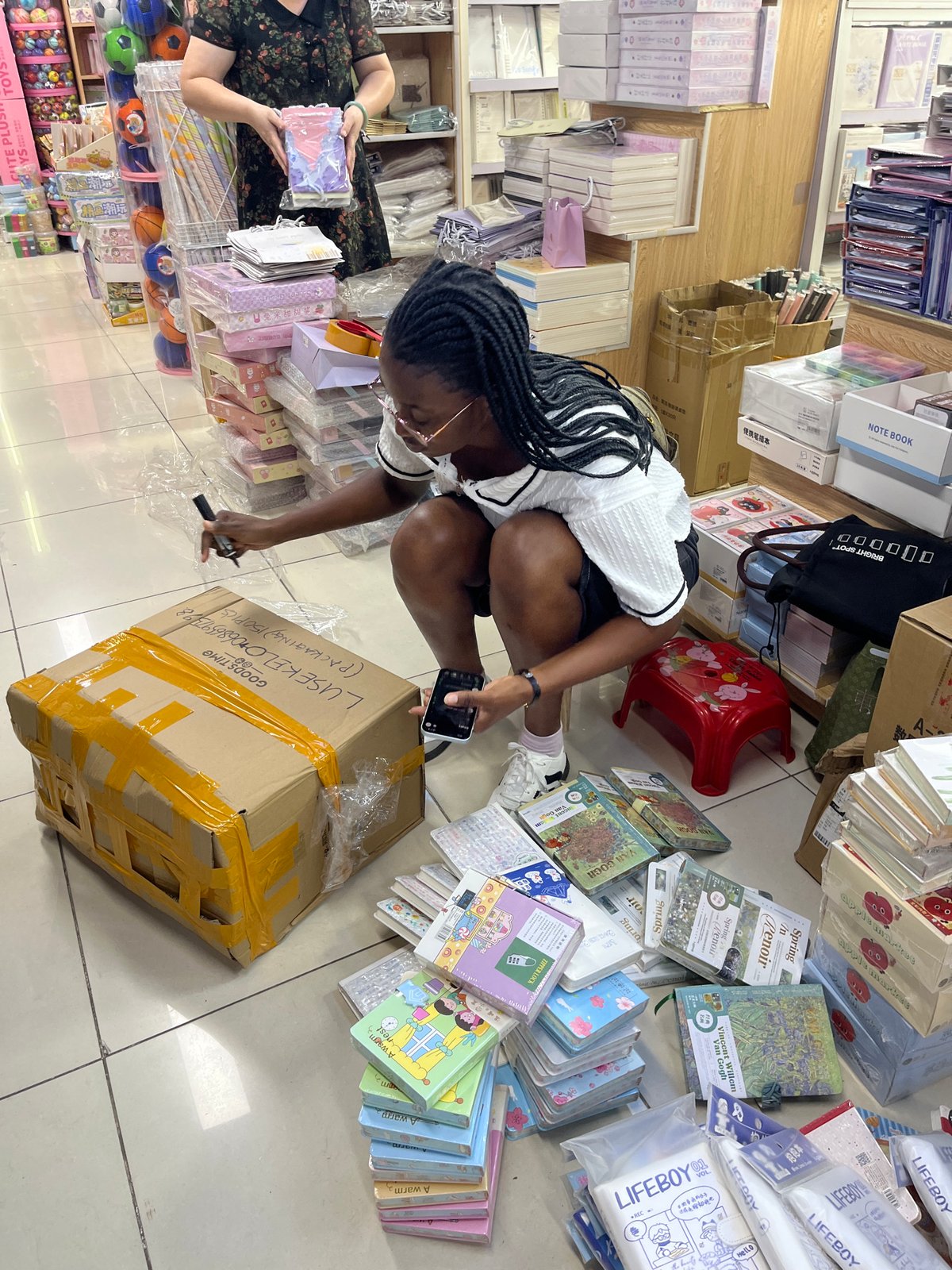 Inside a busy Liwan District stationery shop, customers and staff at work