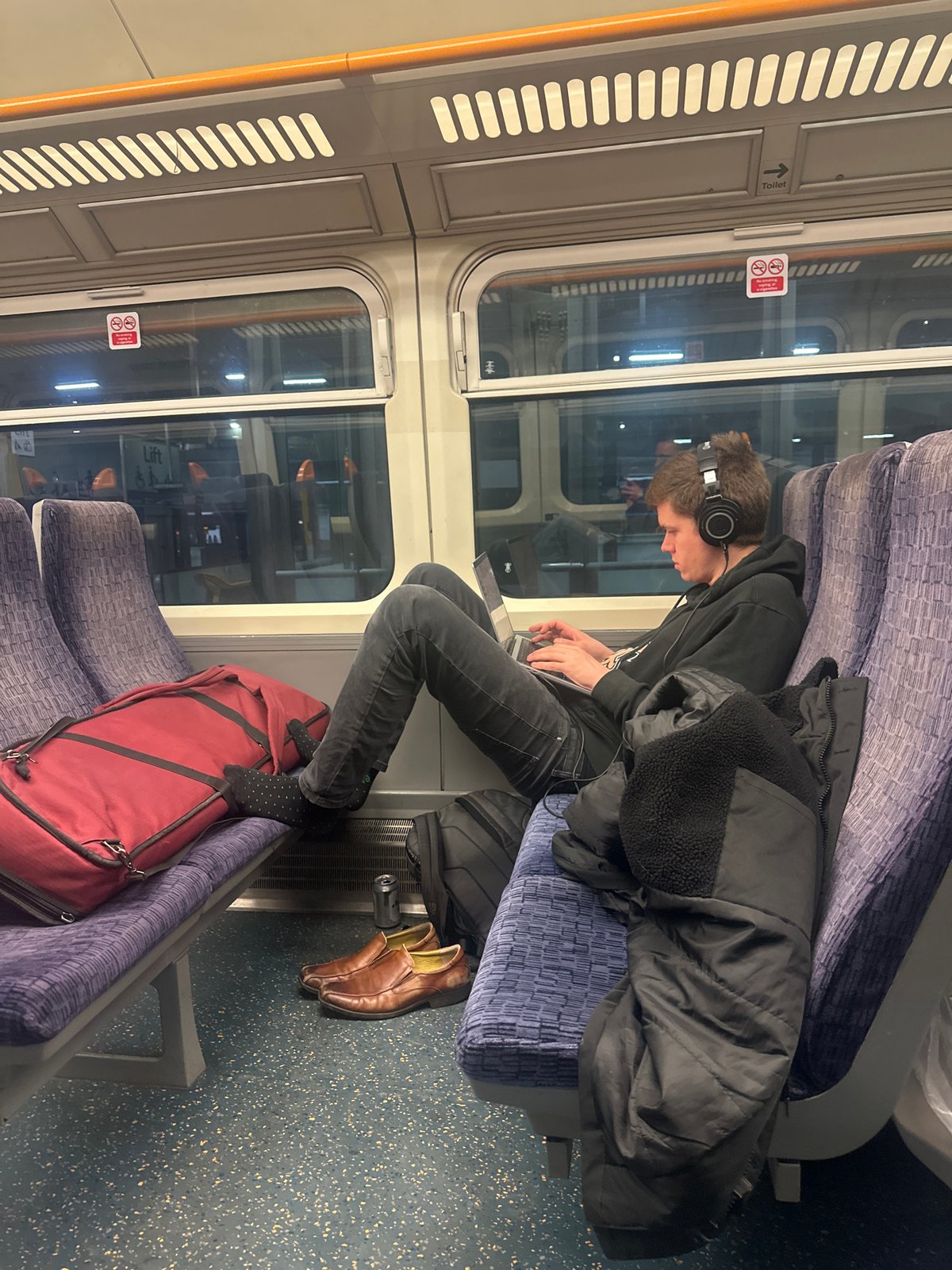 Late night commuter works on laptop during London train journey