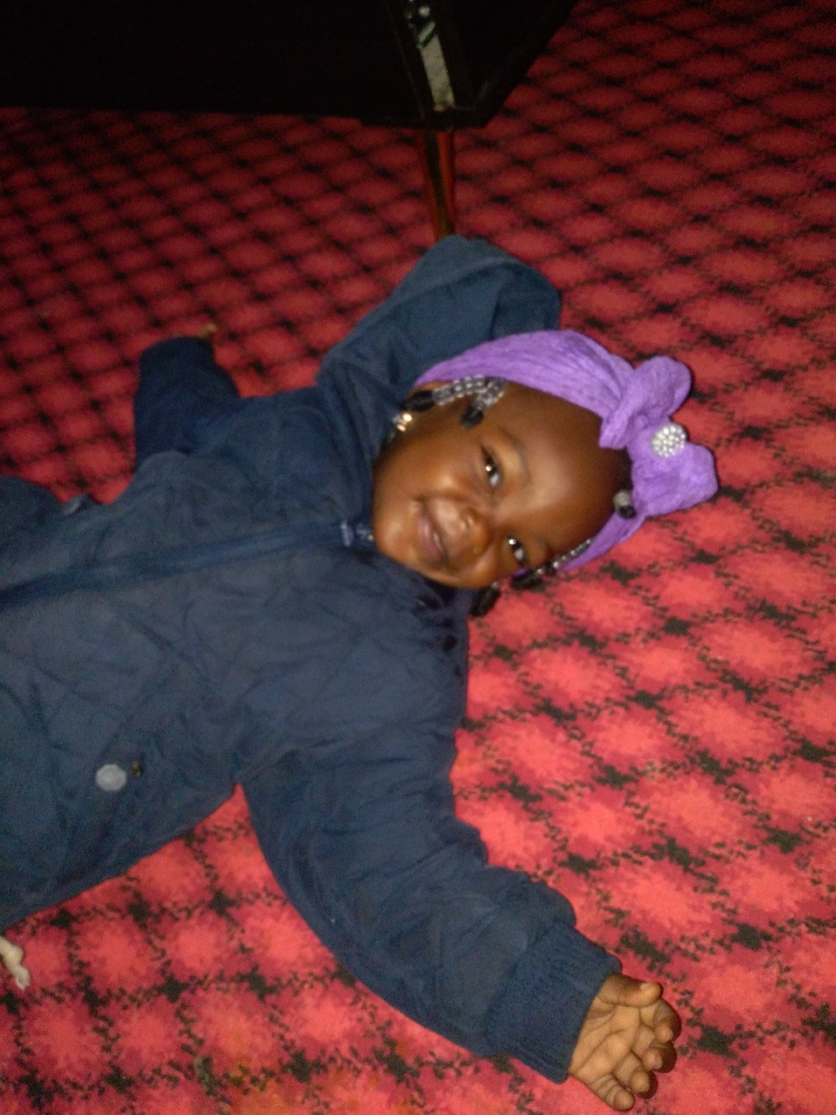 Child plays on patterned carpet during indoor photo session