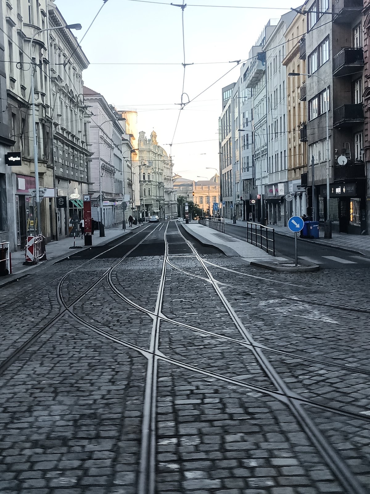 Rainy morning traffic on a cobblestone street near Prague's National Museum