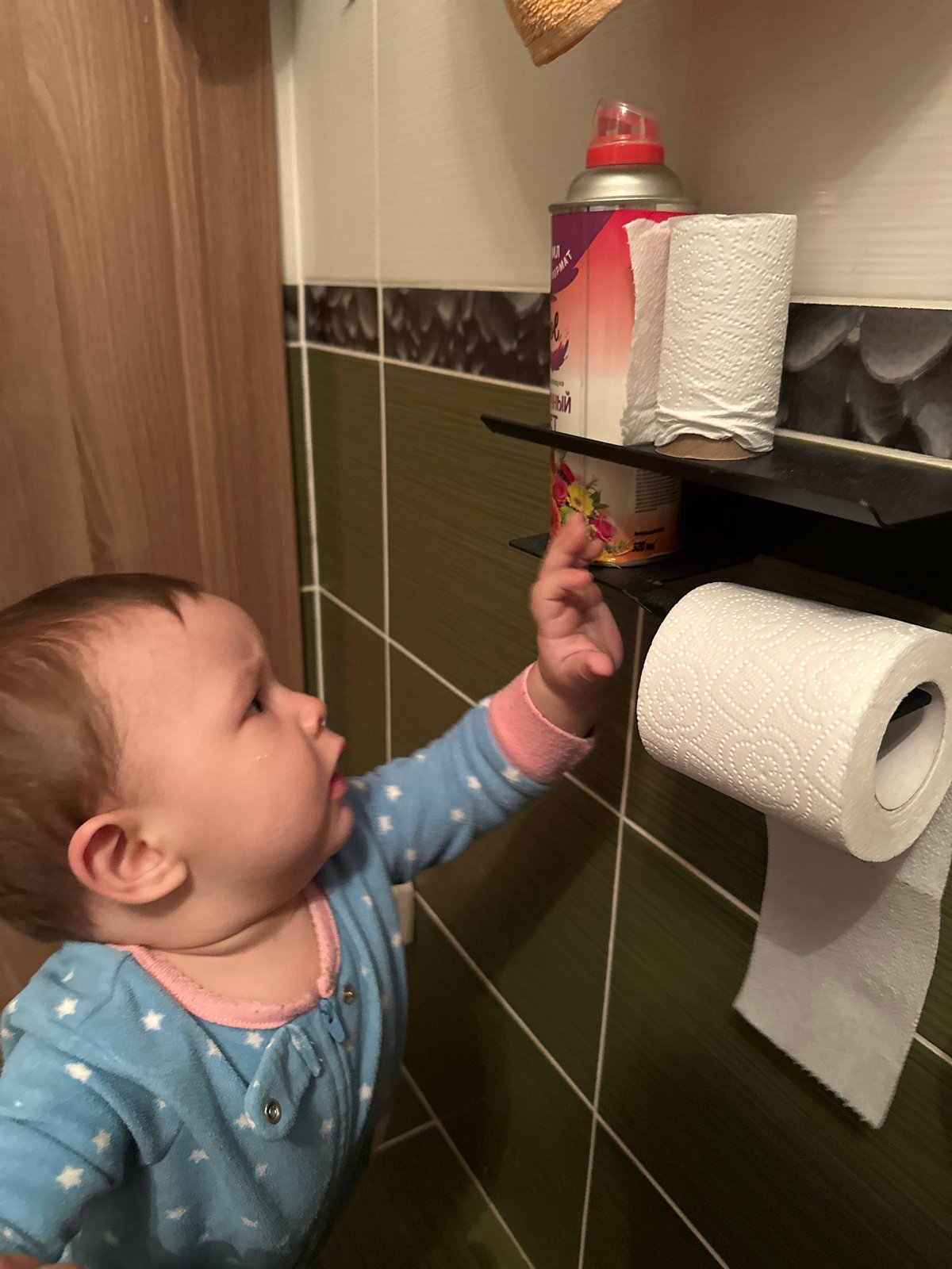 Baby in star pajamas plays with a slinky on the floor