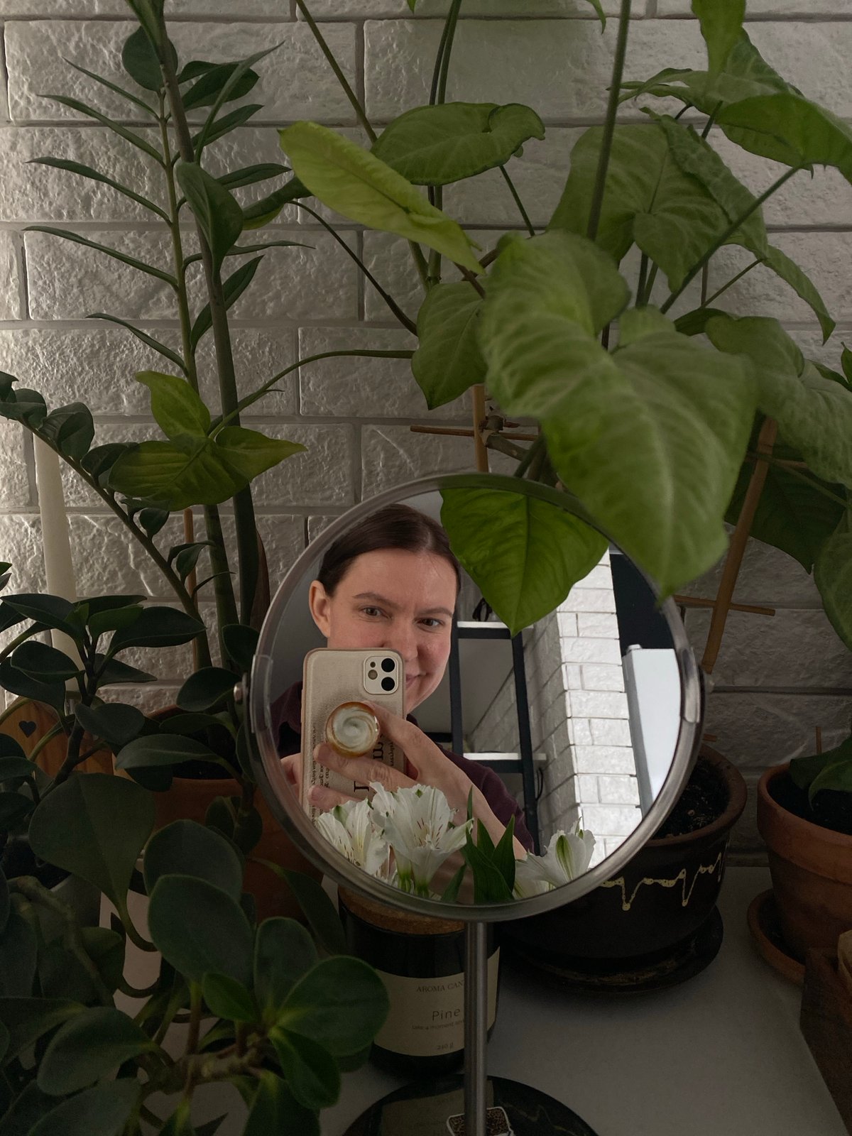 Person photographs white flowers in bedroom mirror selfie session