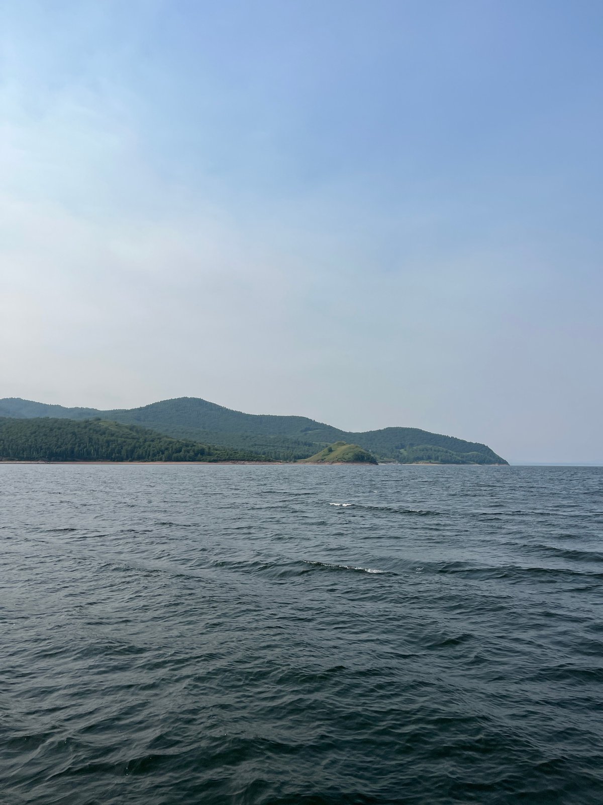 Dark water meets forested hills on a Siberian shoreline