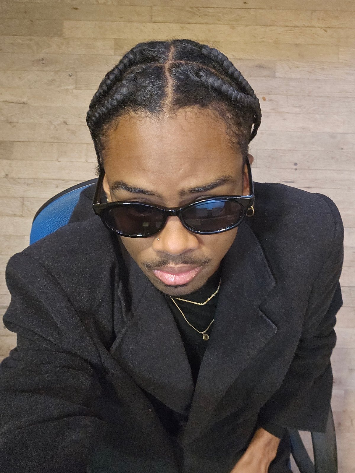 Man in sunglasses sits on blue chair indoors in Paris