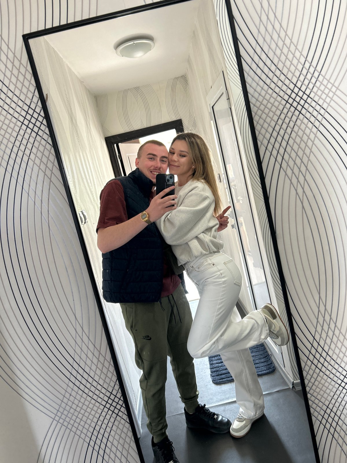 Couple takes mirror selfie in patterned reflective space, Sofia