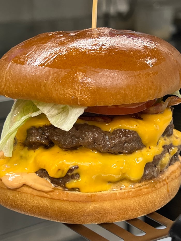 Double cheeseburger preparation documented in Budva, Montenegro