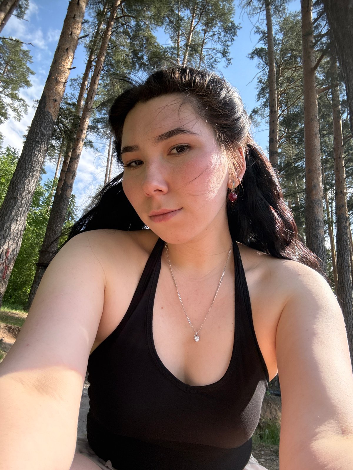 Woman takes selfies by water in Izhevsk forest setting