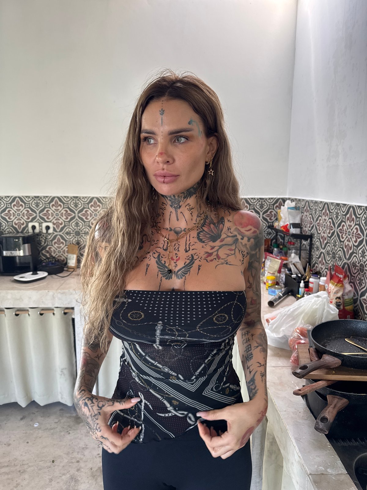 Tattooed woman photographed in kitchen area, North Kuta