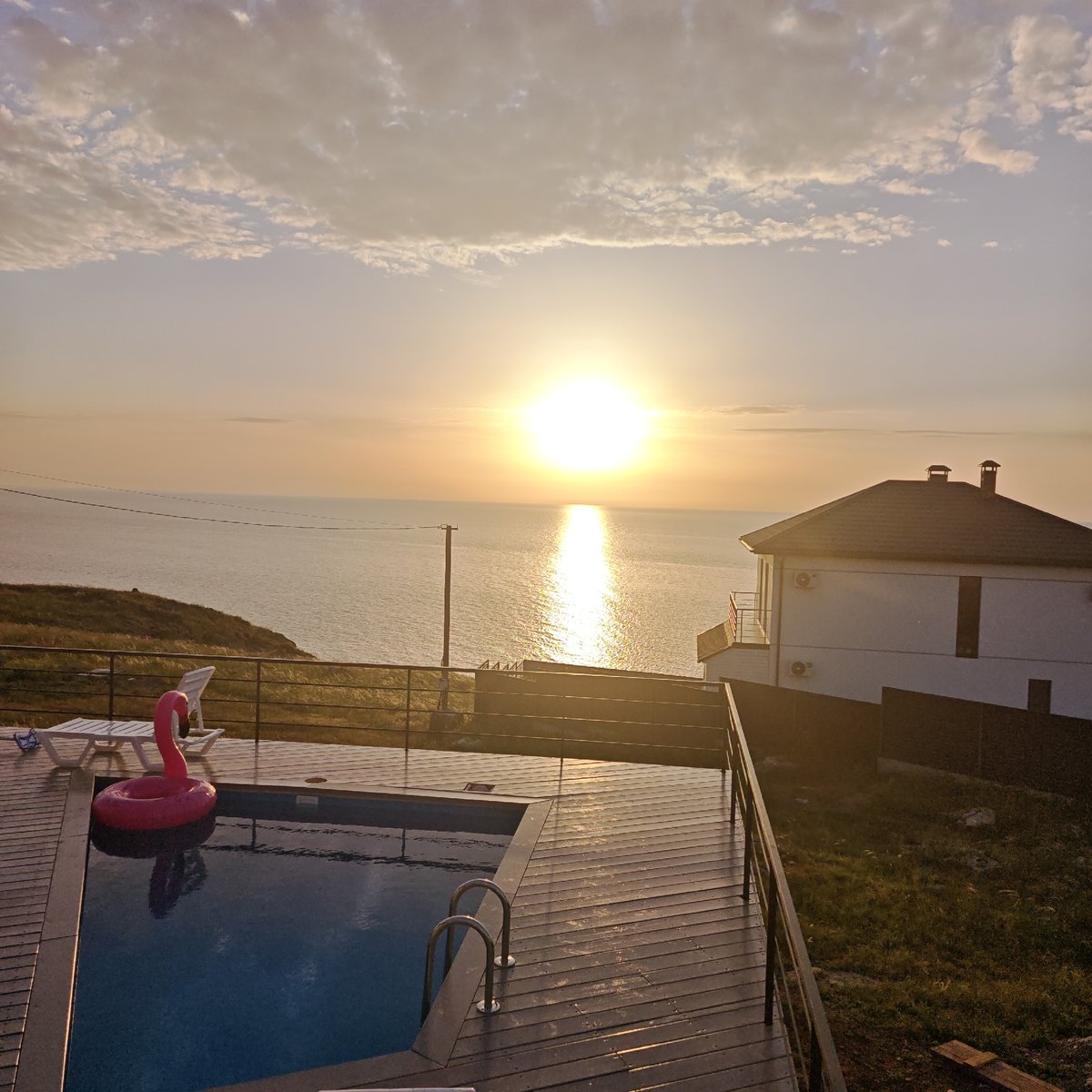 Pink flamingo float spotted in pool during ocean sunset