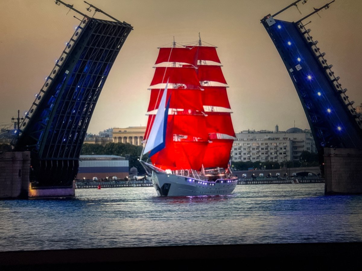 Red-sailed tall ship passes a moonlit Russian city at dusk