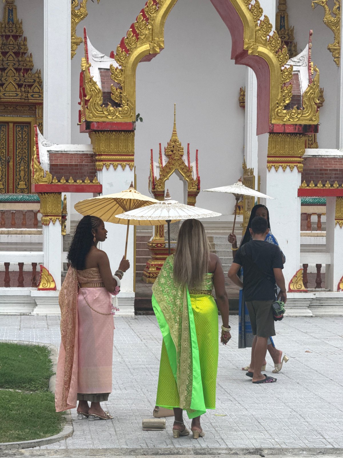Traditional dress and ornate temple architecture in Chalong