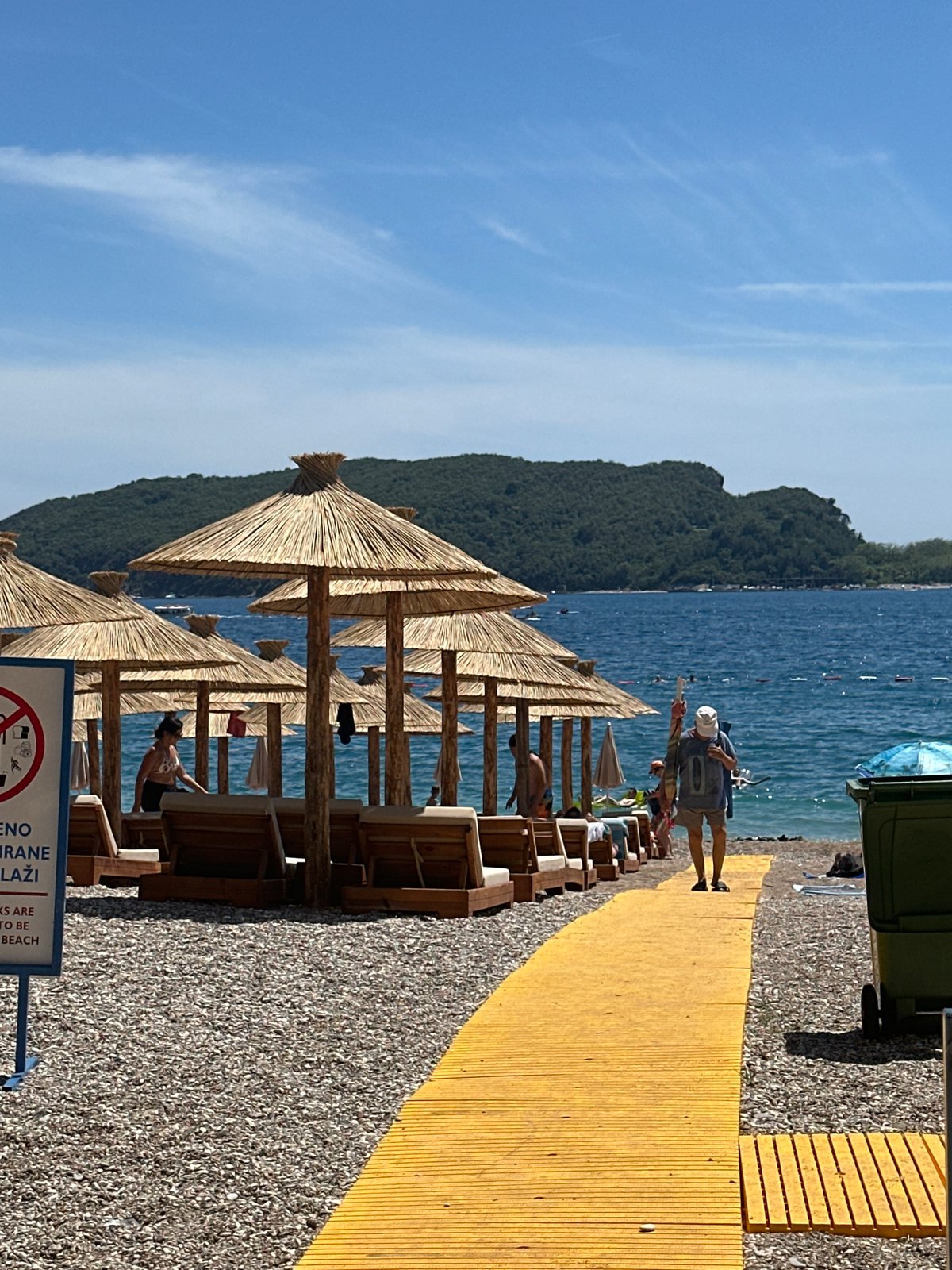 Sun, loungers, and a stone pier on Budva's pebble beach