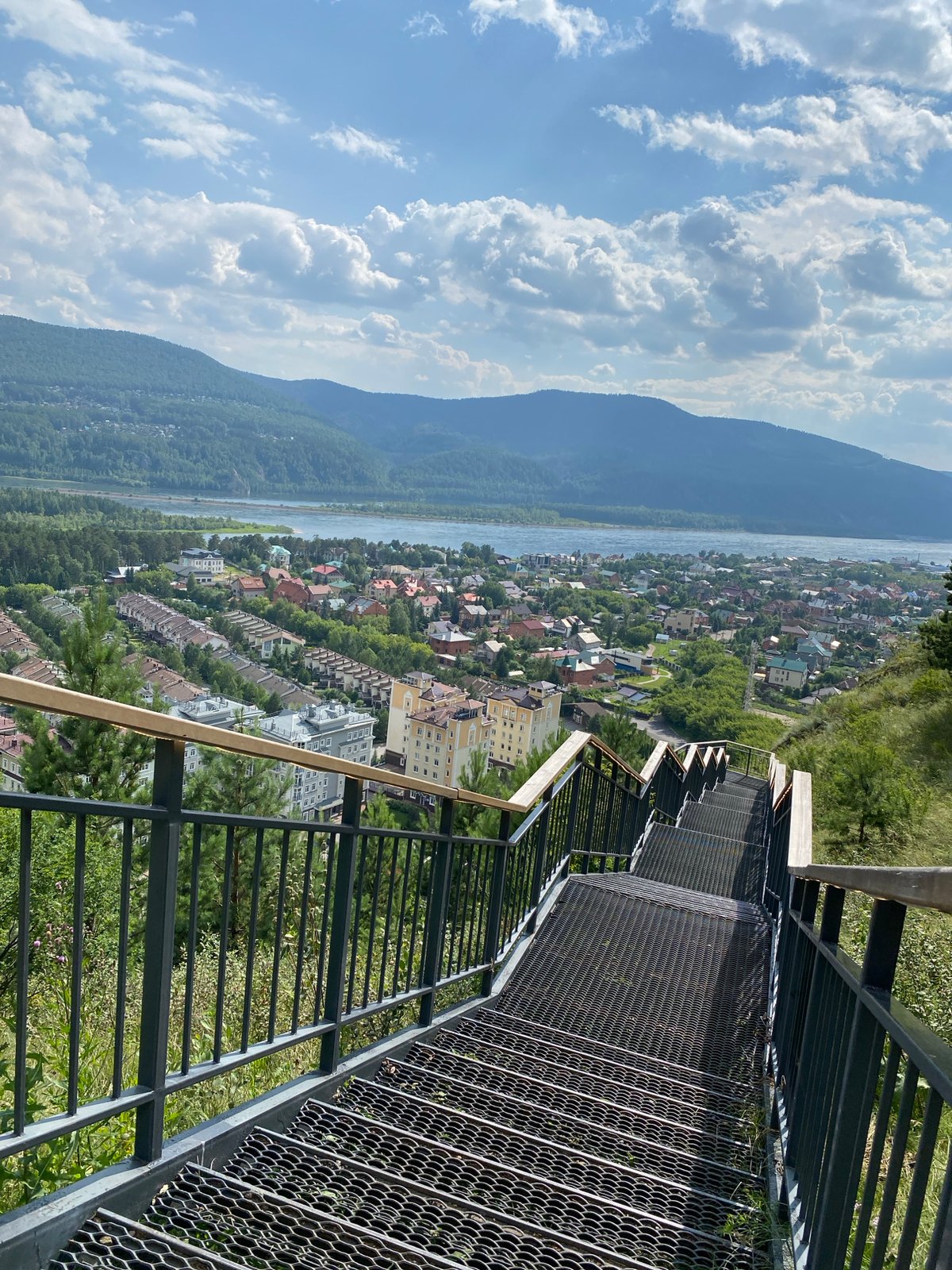 River town panorama from a hilltop overlook with bench and stairs
