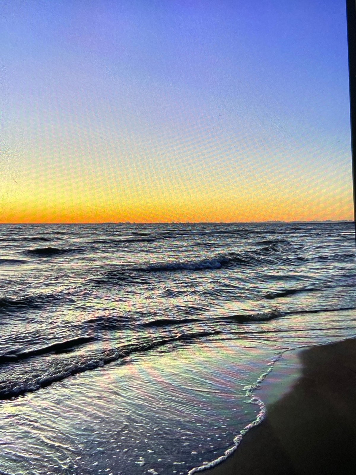 Sun low on the ocean horizon, coast calm and golden