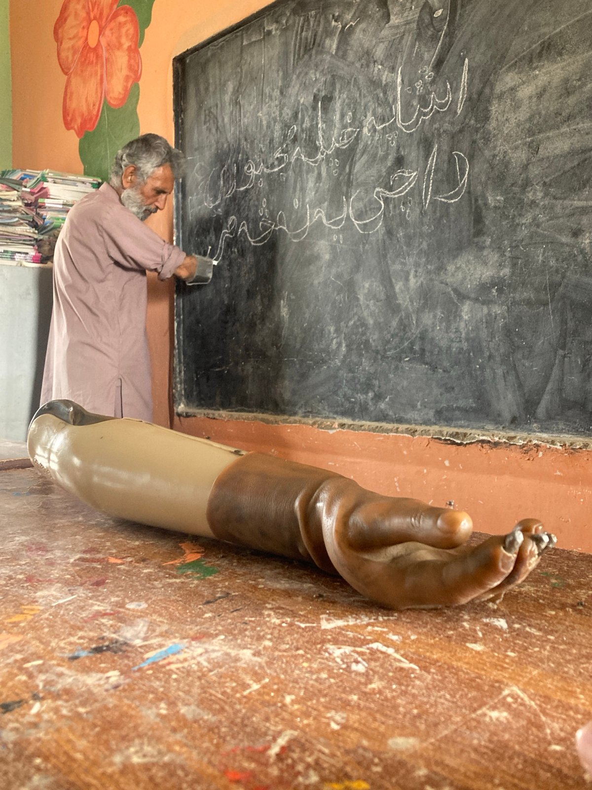 Teacher writes on blackboard in unidentified classroom