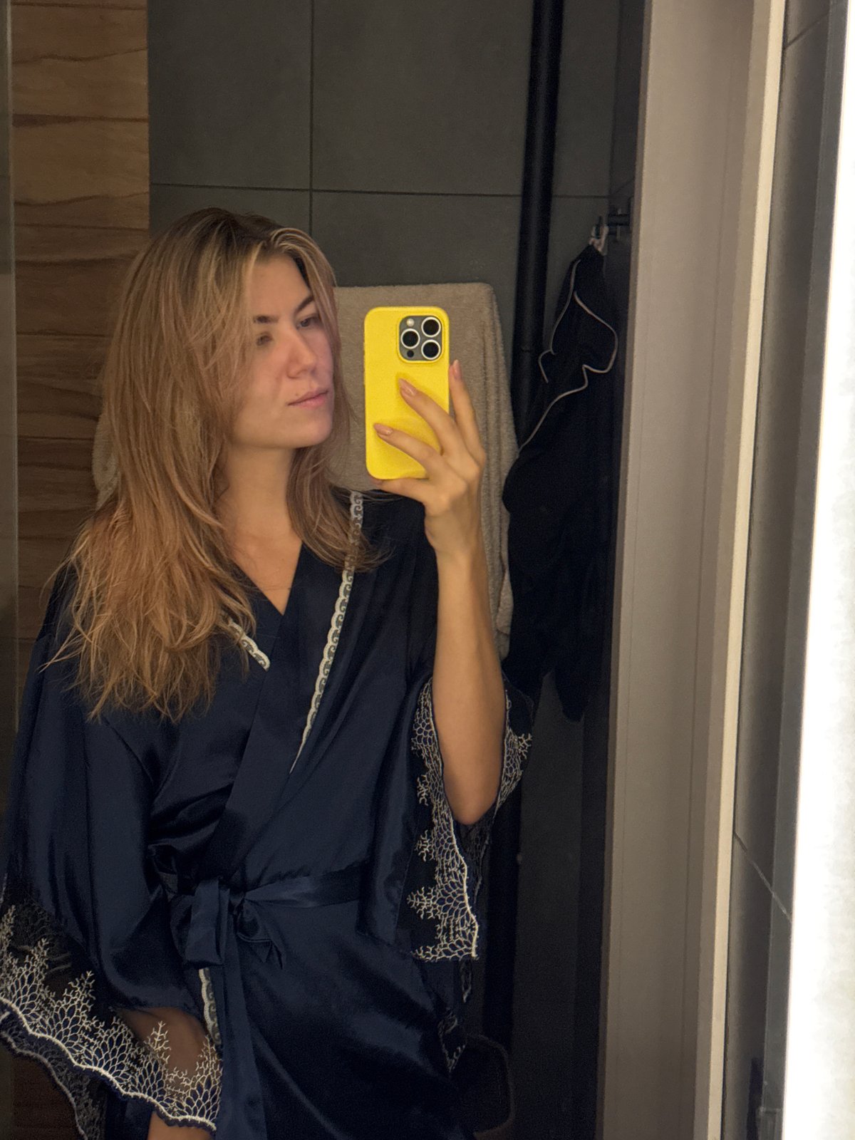 Woman takes bathroom mirror selfies with yellow phone