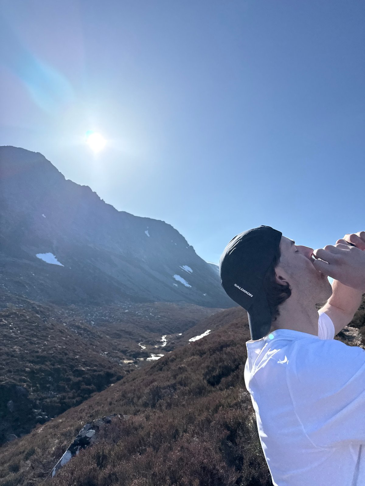 Hiker drinks from hands in snowy mountain terrain