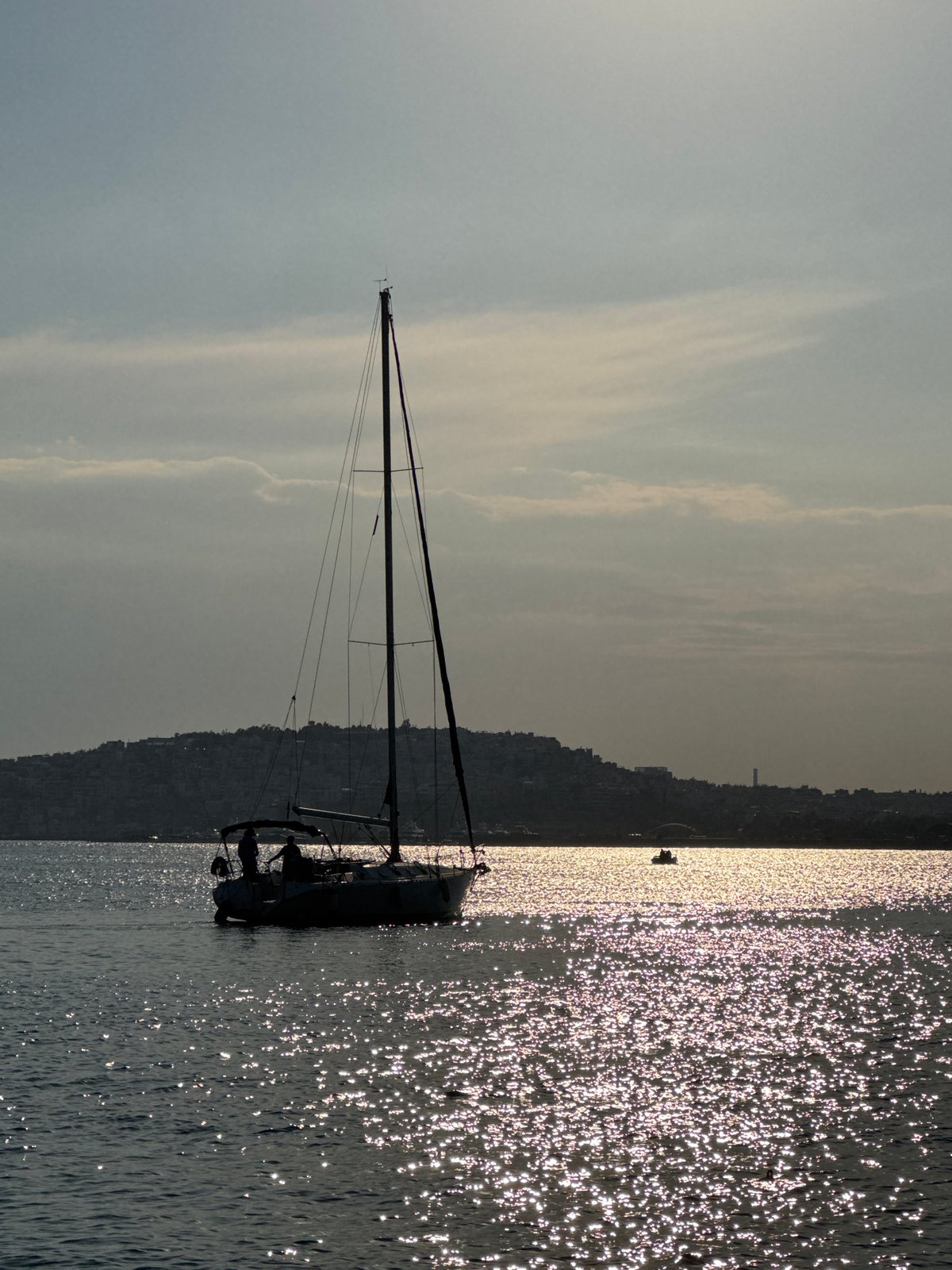 Sailboats silhouetted against the Athenian coastline in afternoon light