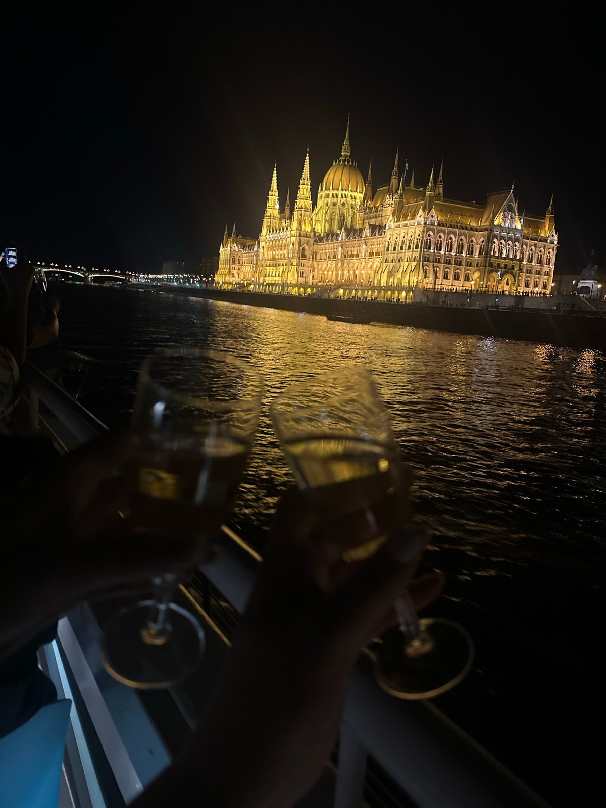 Champagne glasses raised with Parliament lit up behind