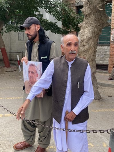 Protesters hold photos during demonstration in Quetta, Pakistan