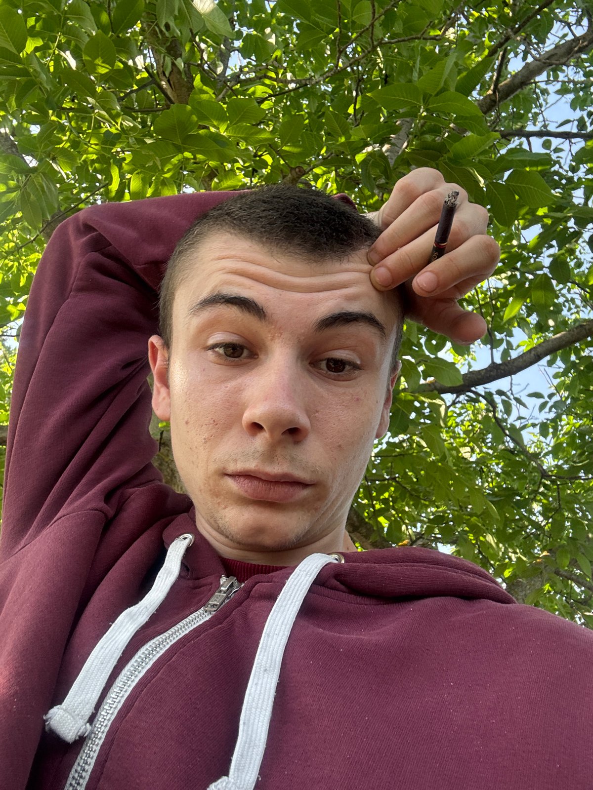 Man smoking cigarette under trees near Škoda in Oriahovo