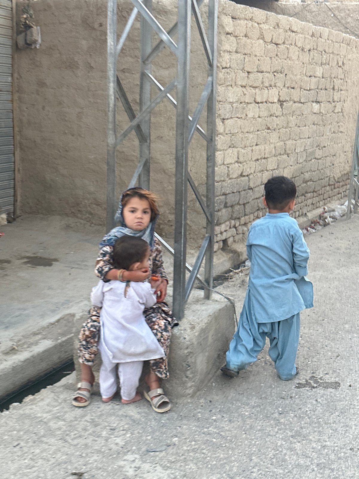 Kids on a Quetta street, traditional clothing, everyday moment.