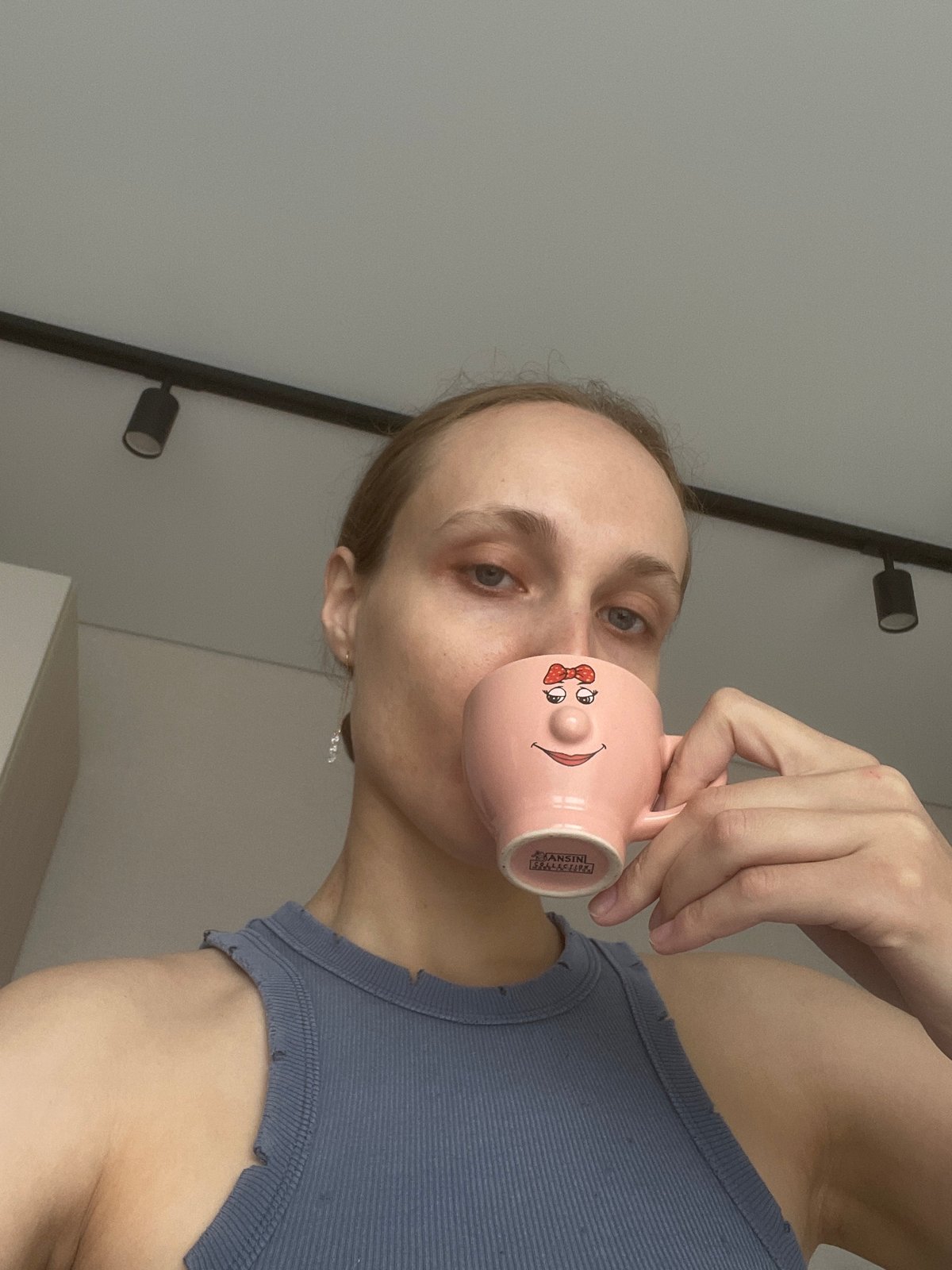 Woman photographed with mug and flowers indoors