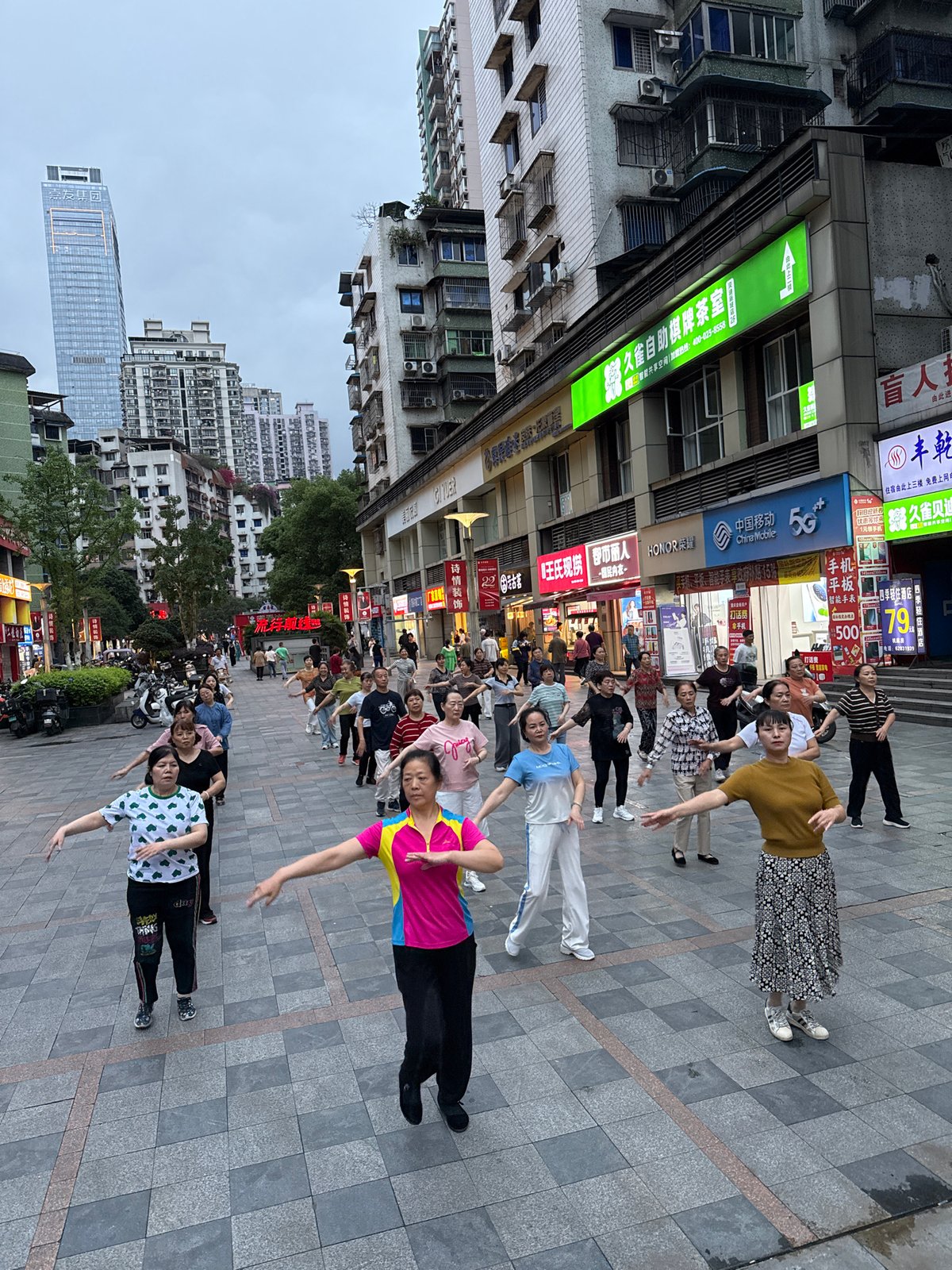 Women perform group dance exercises in Chinese public plaza
