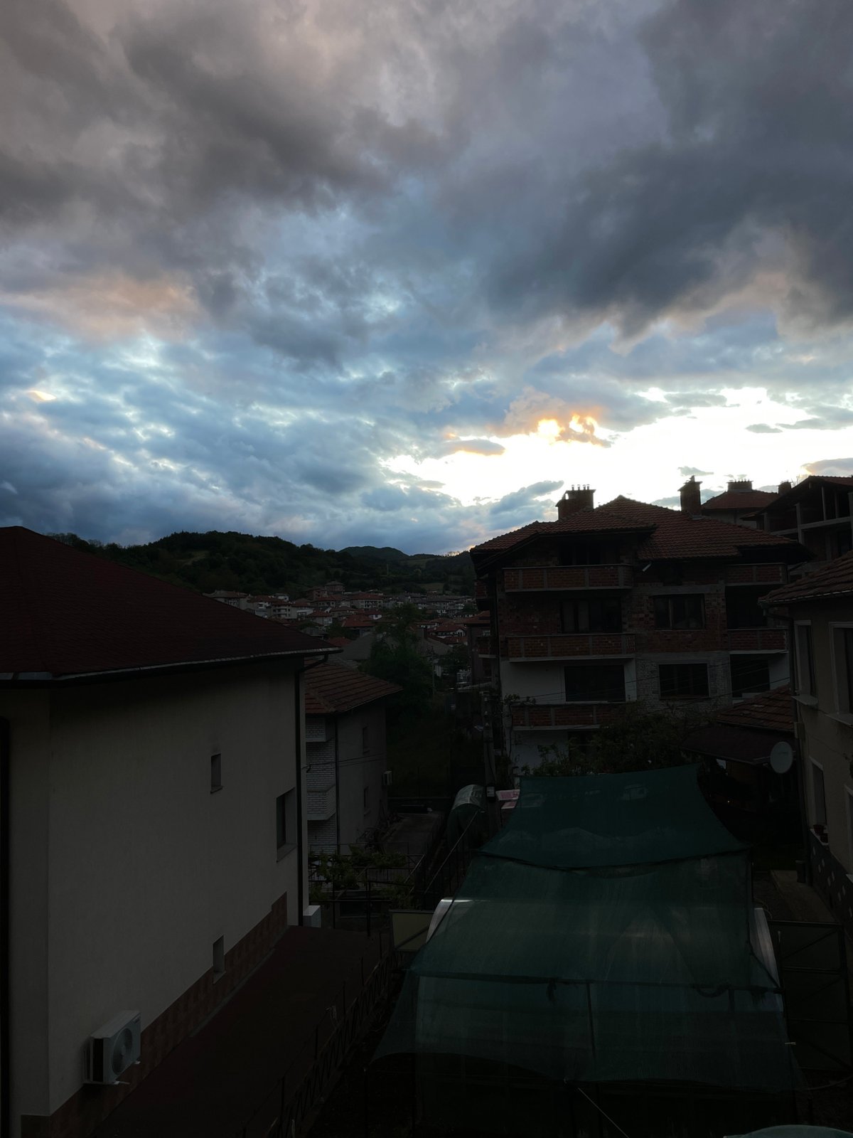 Dramatic clouds captured over Bulgarian hillside town during sunset hours