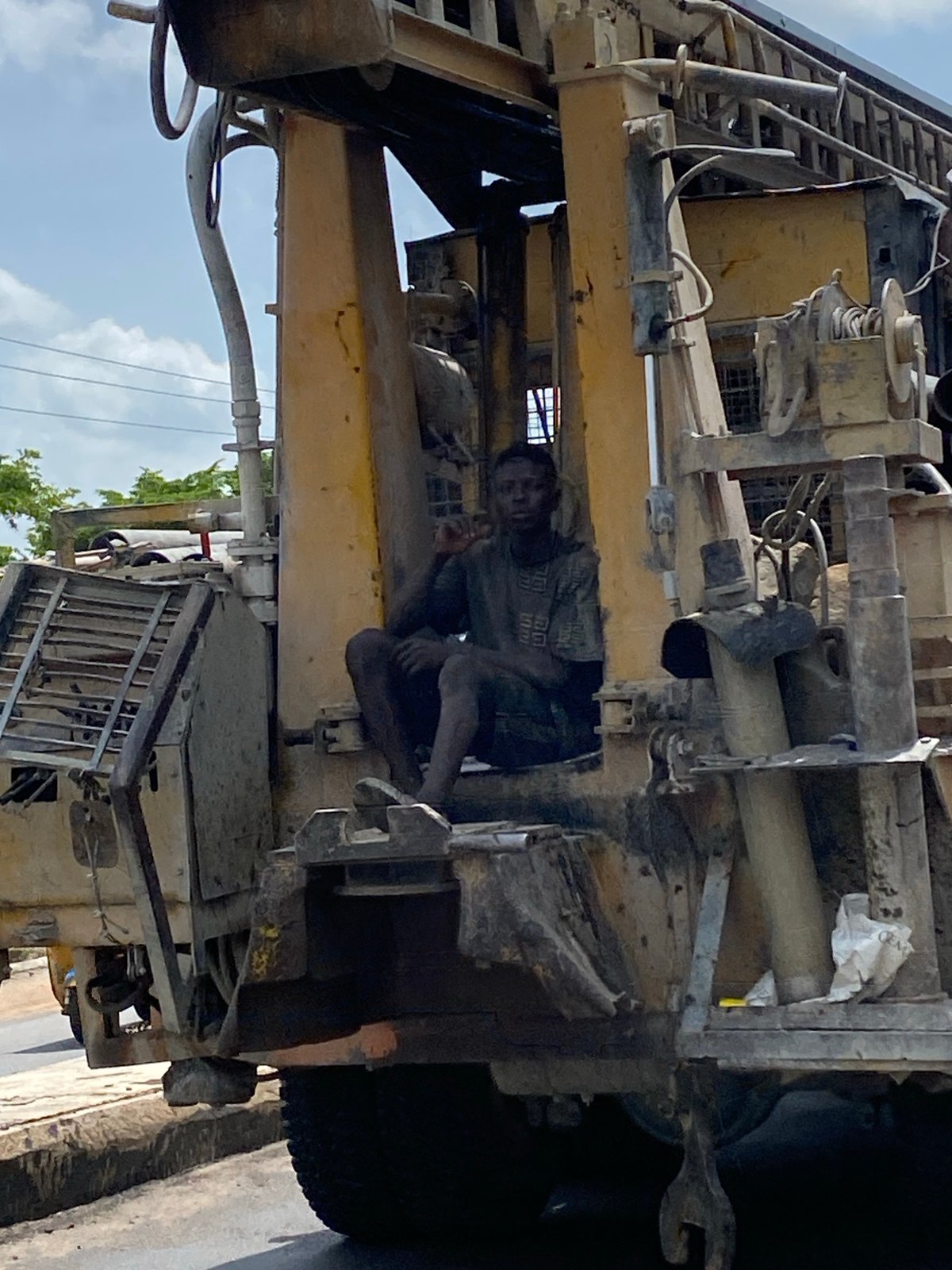 Man sits inside yellow machinery on Lokoja road