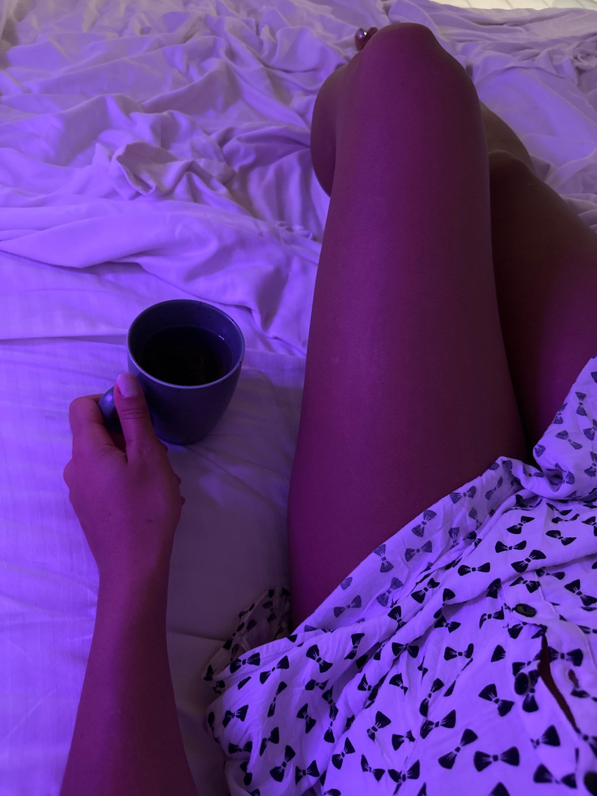 Purple-lit bedroom evening with coffee and rumpled white sheets