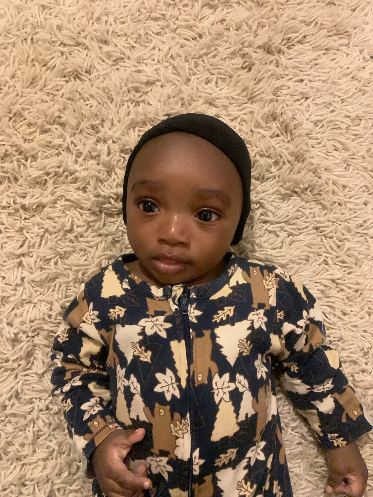 Baby in patterned outfit photographed on rug in Nigeria