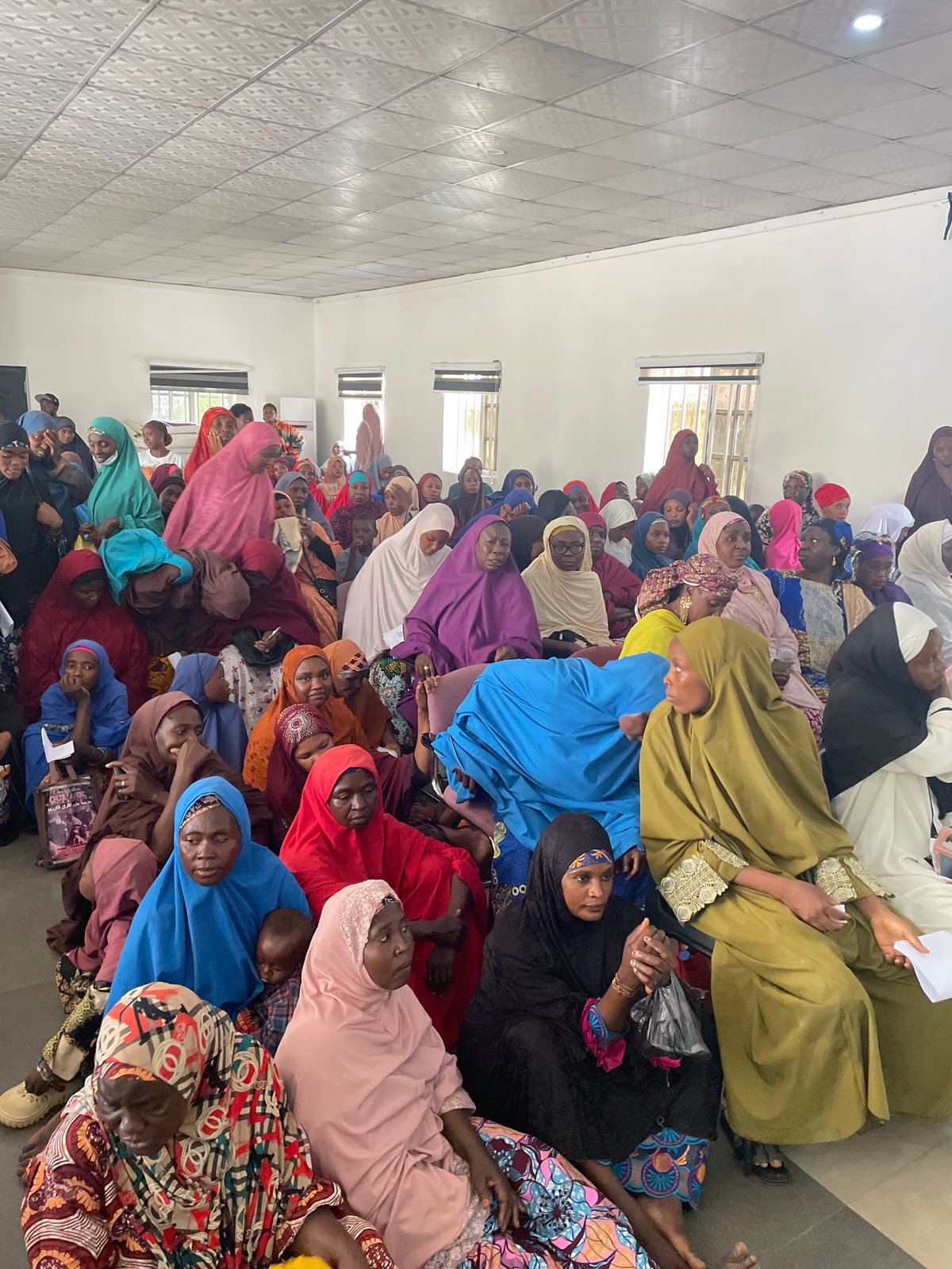 Women gather in colorful attire on floor in Jos