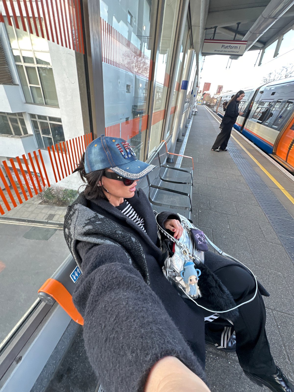 Person with silver handbag waits at London train platform