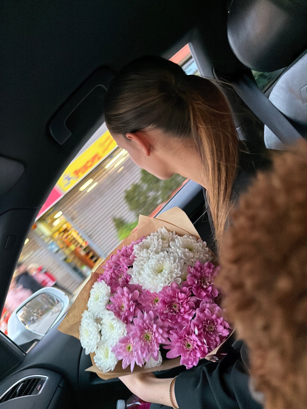 Woman carries flower bouquet in moving car in Sofia