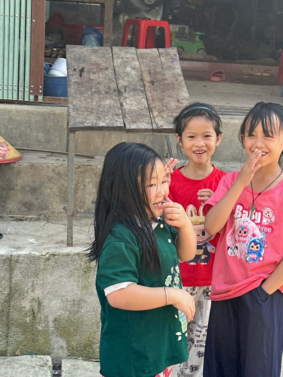 Three girls gather outdoors in Vietnamese commune