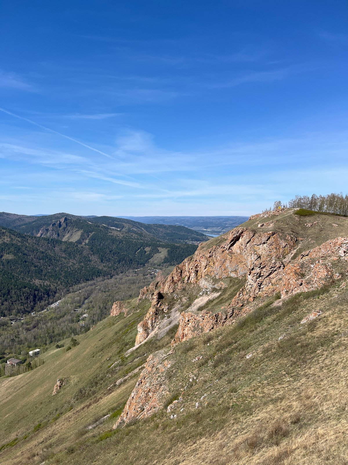 Hikers gather at mountain viewpoint near Krasnoyarsk under clear skies